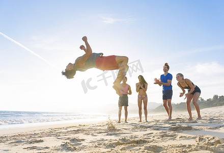 一群朋友在海滩上看朋友翻筋斗