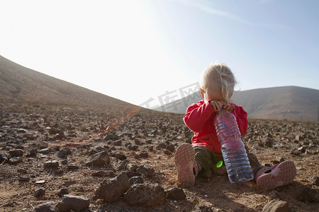 山水人摄影照片_沙漠里拿着一瓶水的蹒跚学步的孩子