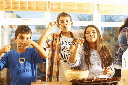 儿童培育摄影照片_儿童在厨房品尝蛋糕混合物