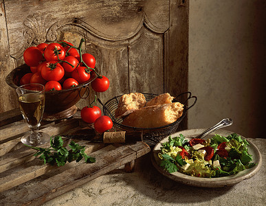 干葡萄藤摄影照片_传统的地中海食物展示葡萄藤上的西红柿硬皮的白色恰巴塔面包羊乳酪沙拉和晒干的西红柿沙拉叶香菜配一杯酒
