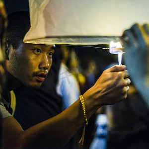 东南亚人摄影照片_泰国清迈一名年轻男子为纸灯节点灯