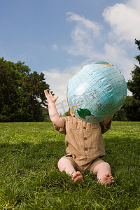 坐在球上的男孩摄影照片_带着充气地球仪的公园里的婴儿