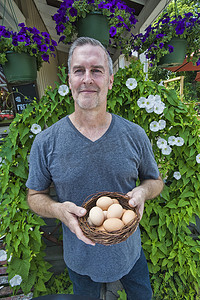 企业餐厅摄影照片_咖啡馆老板在餐厅前提着一篮子新鲜鸡蛋