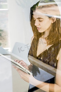 一名使用数字平板电脑的年轻女子通过玻璃拍照