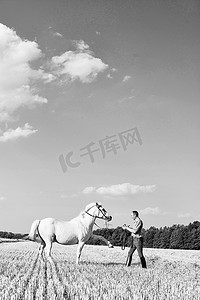 人在野外训练白马的黑白图像