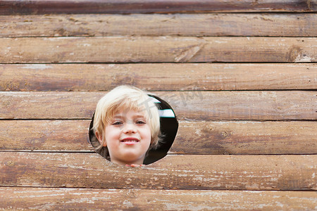 声洞摄影照片_从玩具屋的洞里往外看的男孩