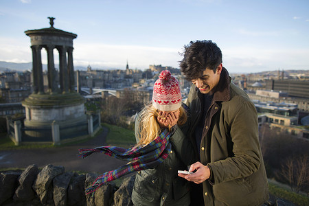 一对年轻夫妇在卡尔顿山上以苏格兰首府爱丁堡市为背景自拍