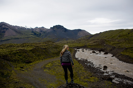 冰岛河边望着山脉的中年妇女的背影