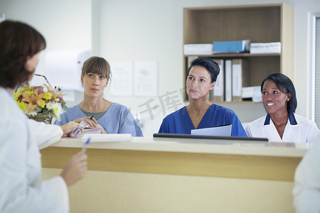 性病摄影照片_女医生在医院护士站与护士座谈