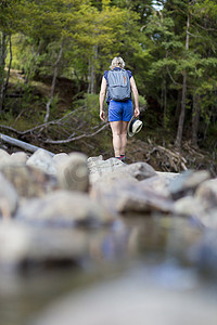 徒步旅行者在浅溪流中的石头中行走新西兰北岛外马森林