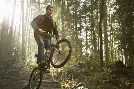 一名年轻人在森林里骑山地自行车做特技表演