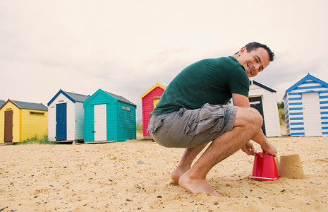 快乐男士在海滩上堆沙堡