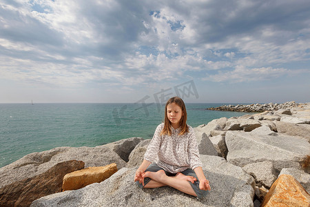 在海滩的岩石上冥想的女孩