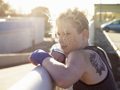 年轻女子拳击手靠在城市栏杆上的肖像
