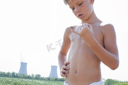 小男孩用小手指抓着蝴蝶背景是核电站