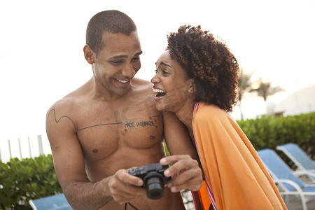 巴西里约热内卢一对情侣在酒店泳池边的数码相机前大笑