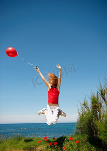 年轻女孩带着红色气球跳跃