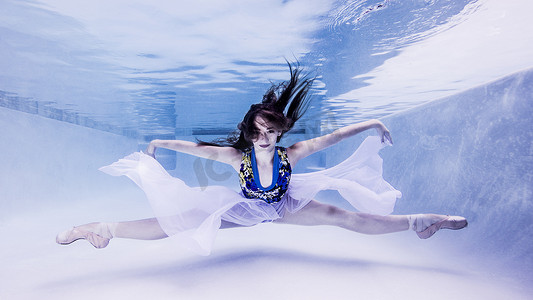 十几岁的女孩穿着芭蕾舞鞋以舞蹈的姿势在水下观看