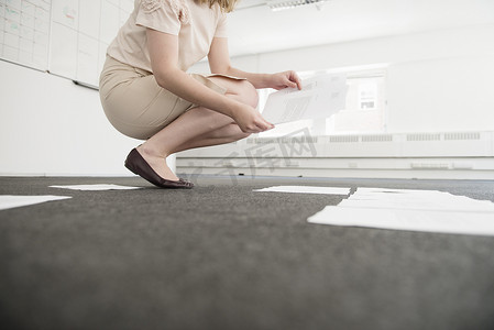 一位年轻的女商人在空荡荡的办公室地板上整理文件