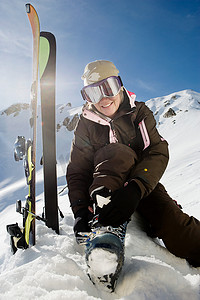 冬季雪地靴摄影照片_成熟的滑雪女运动员紧固靴