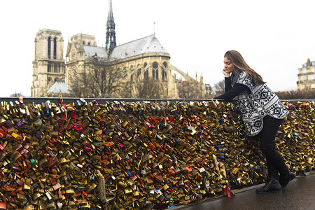 背景是巴黎圣母院的桥靠在爱情锁上的年轻女子法国