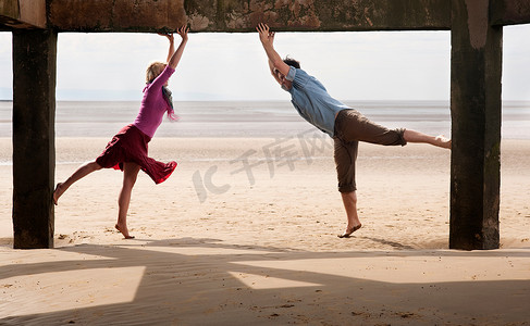 灵活性摄影照片_一对夫妇在海滩上锻炼