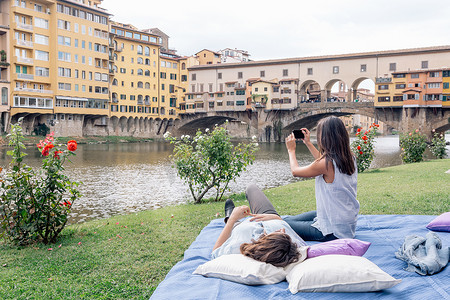 意大利托斯卡纳佛罗伦萨阿尔诺河上的一对女同性恋夫妇用数码相机拍摄的韦奇奥桥
