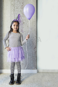 年轻女孩的肖像穿着派对服装手持紫色气球