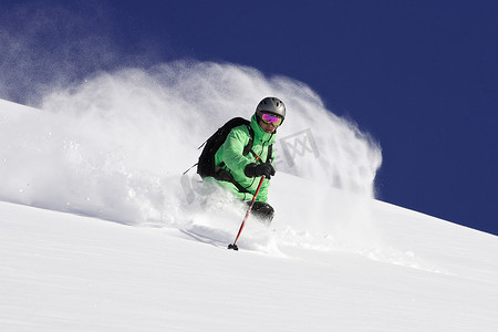 滑雪护目镜摄影照片_雪山斜坡上的滑雪者