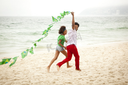 旗子摄影照片_巴西里约热内卢一对情侣在海滩上玩旗子