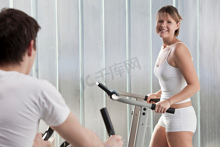 健身器摄影照片_微笑的女人使用健身器