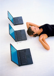 一名妇女手持笔记本电脑躺在地板上