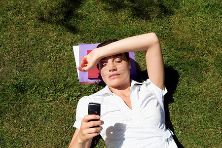 女商人躺在草地上发短信