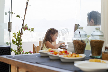 家庭餐摄影照片_父女俩坐在阳台的早餐桌上健康的食物摆在前面