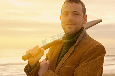 海滩上的一名男子拿着旧板球棒