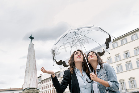 意大利托斯卡纳佛罗伦萨圣玛丽亚·诺维拉广场一对女同性恋夫妇撑着伞手握雨伞仰望天空