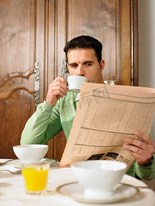 一名男子在早餐桌上看报纸