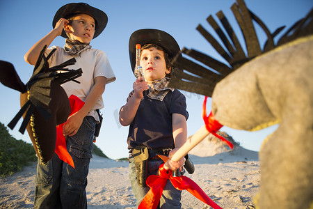 两兄弟装扮成牛仔拿着玩具枪和业余爱好马的