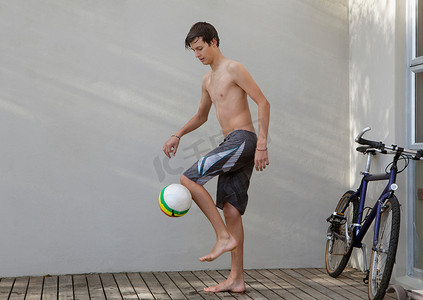 坐在球上的男孩摄影照片_十几岁的男孩玩足球