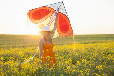 风筝顶棚摄影照片_中年妇女在油菜籽田野上举着风筝