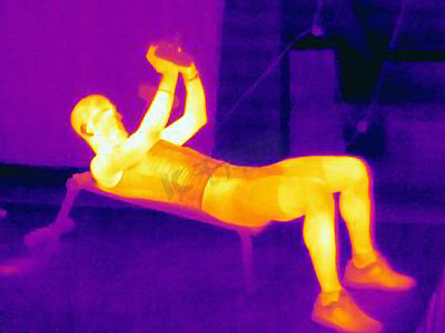 荧光图摄影照片_年轻人杠铃训练的侧视热像这张图显示了肌肉产生的热量