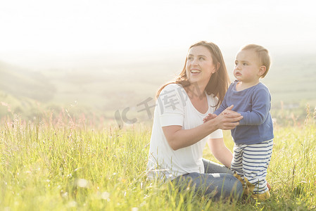 克莱因蓝水波底纹摄影照片_母亲和年幼的儿子坐在田野里