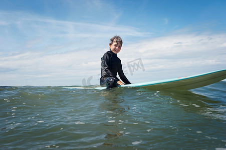 坐在海上冲浪板上的小男孩