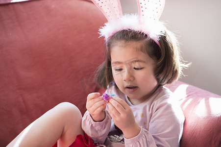 戴着兔耳朵的年轻女孩看着毛茸茸的复活节小鸡