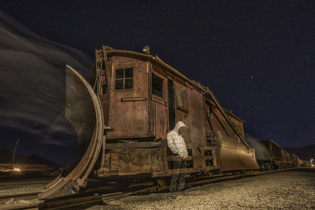 一位戴着帽衫的鬼魂站在废弃的旧火车旁