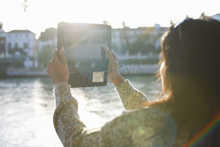 西班牙塞维利亚成年女游客在数码平板电脑上拍摄瓜达尔奇维尔河