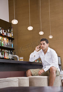 一名男子坐在酒吧里打手机