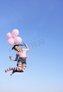 拿着气球在空中跳跃的女孩