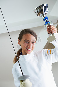 击剑训练摄影照片_微笑的女孩拿着击剑奖杯