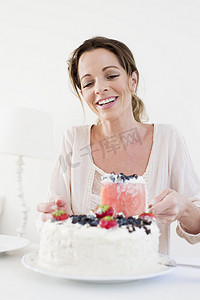 成熟女人端上水果蛋糕低下头微笑着